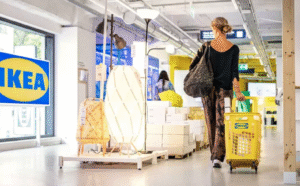 Kundin im IKEA-Möbelhaus mit gelbem Einkaufswagen, Lampen und Kartons; modernes Shopping-Erlebnis.