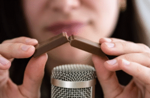 Nahaufnahme einer Person, die eine Schokolade vor einem Mikrofon bricht, geeignet für ASMR-Aufnahmen.